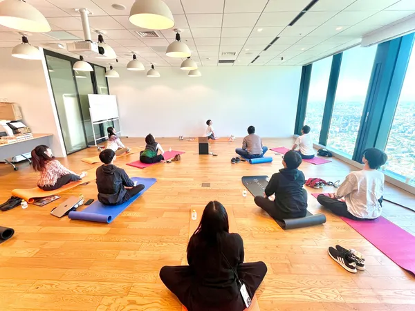 板張りの部屋でヨガマットを敷いてヨガが行われている