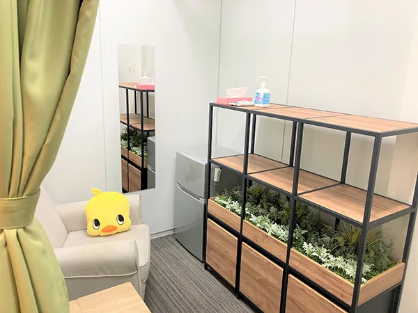 「Nap&Nursing Lounge」写真。ひとりがけのソファー、机、鏡、冷蔵庫、シェルフ、カーテンがあり、ソファーの上にヒヨコのキャラクターのクッションが置かれている